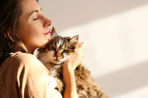 Kobieta tuli kota, czując jego ciepło. To piękny przykład felinoterapii, która przynosi spokój i radość.