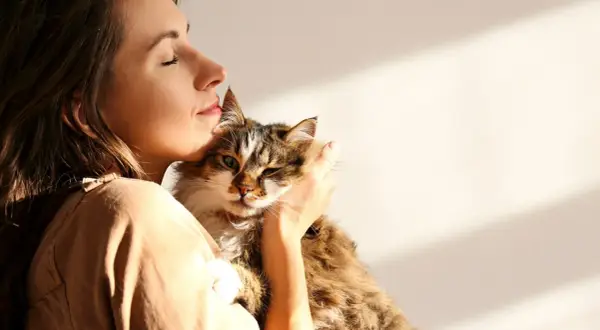 Kobieta tuli kota, czując jego ciepło. To piękny przykład felinoterapii, która przynosi spokój i radość.